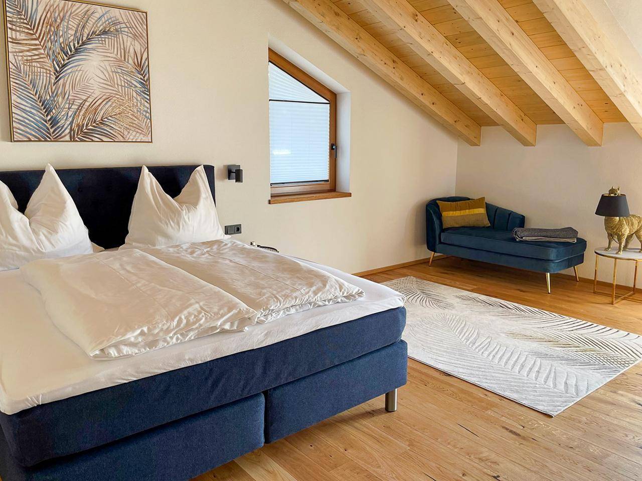 Gemütliches Schlafzimmer mit Holzbalkendecke, Holzboden und schräger Dachschräge.