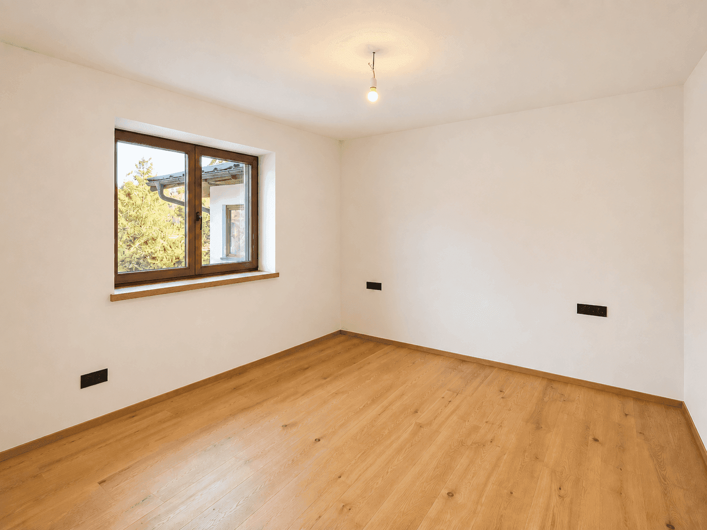 Helles, leeres Zimmer mit Holzfenster und Parkettboden, ideal als Schlafzimmer nutzbar.