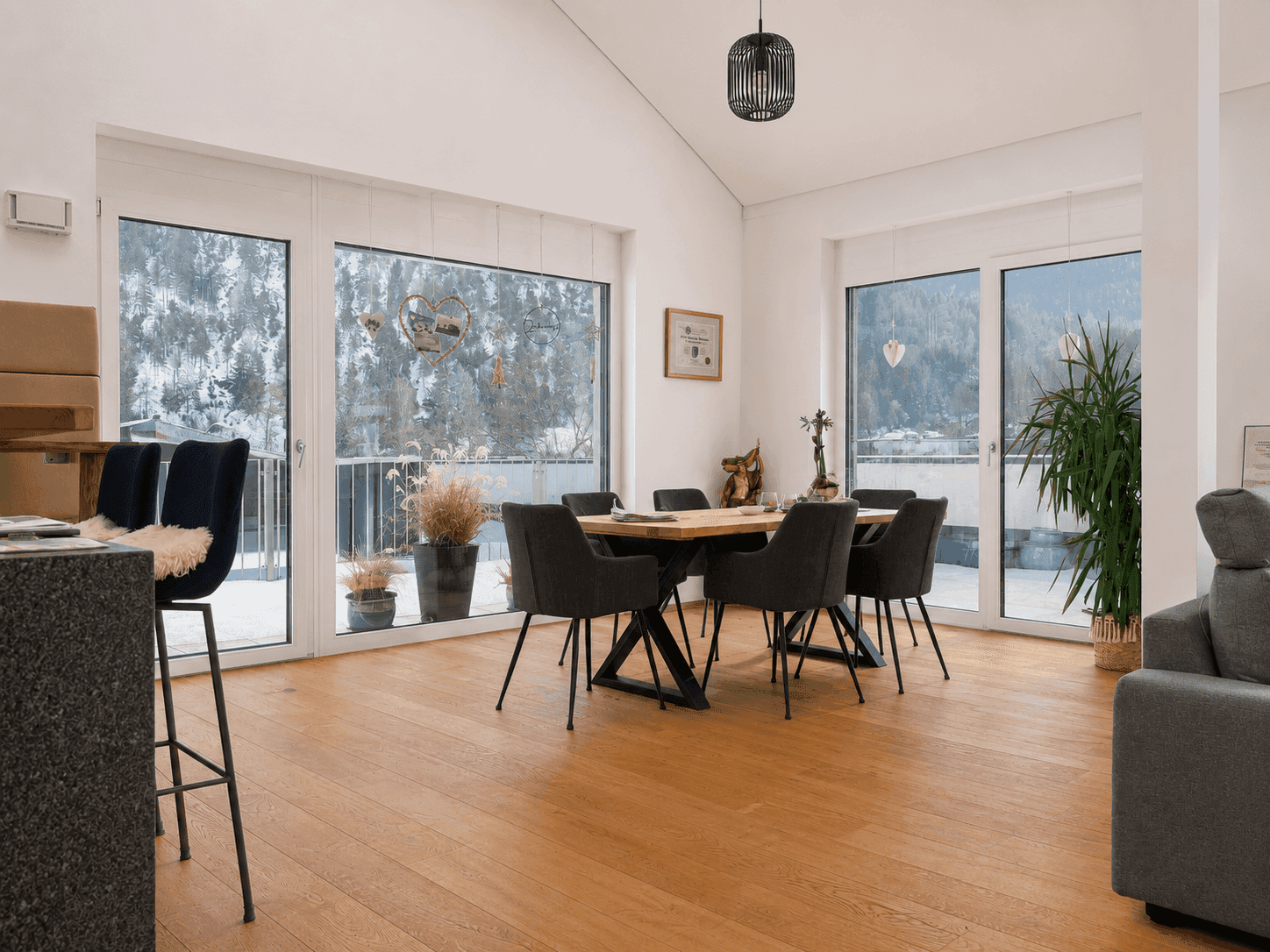 Geräumiger Essbereich mit Holztisch, modernen Stühlen und weitem Blick auf die verschneite Landschaft.