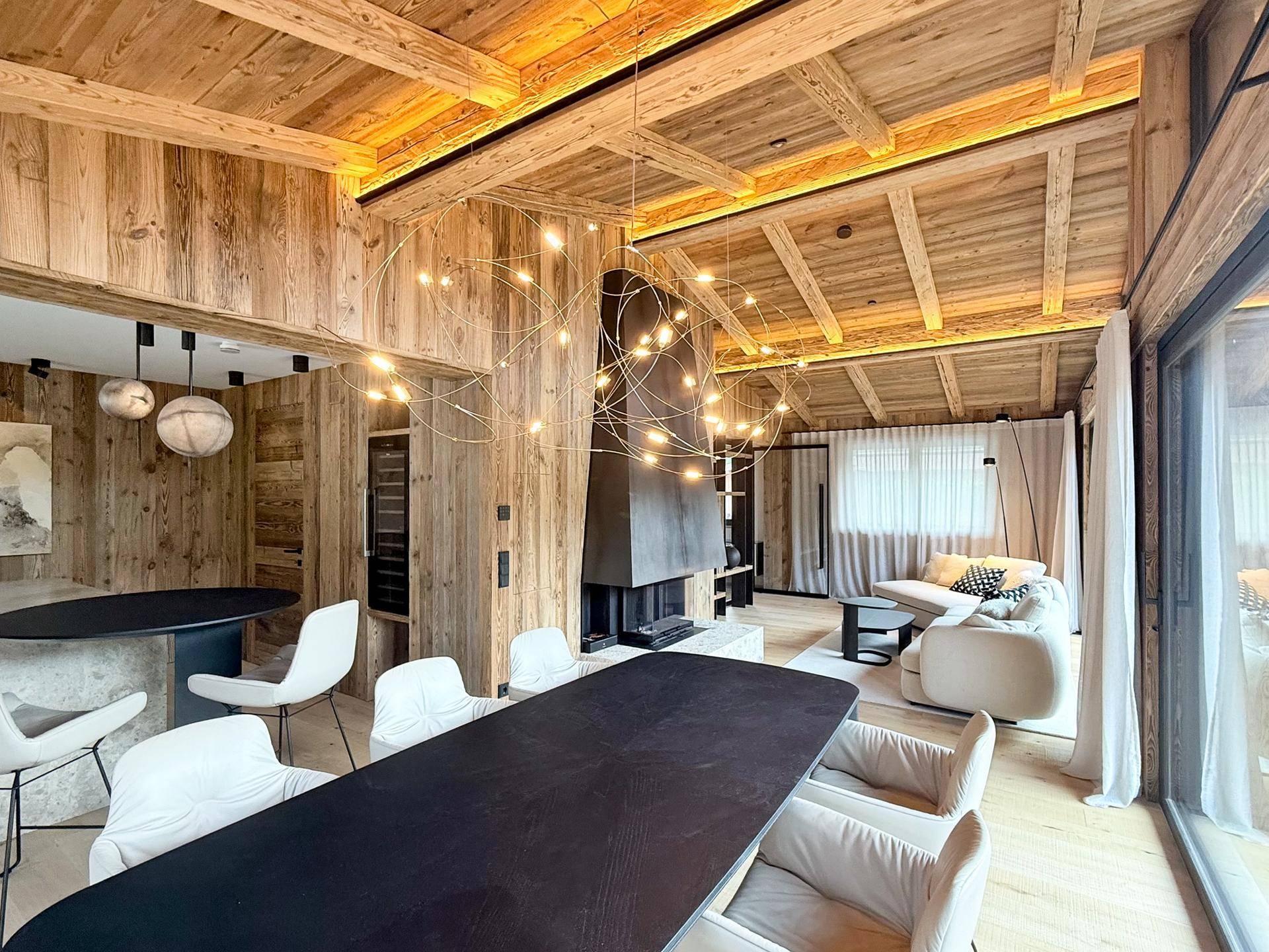 Eleganter Essbereich mit großer Pendelleuchte, Holzwänden und Blick auf den Wohnbereich.
