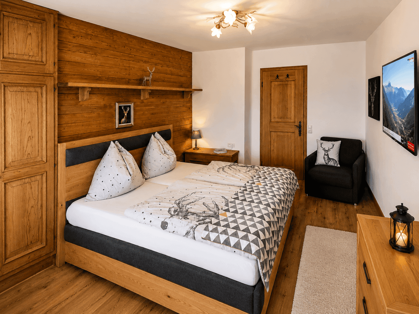 Gemütliches Schlafzimmer mit Holzwand, Doppelbett und traditionellen alpinen Dekorationen.