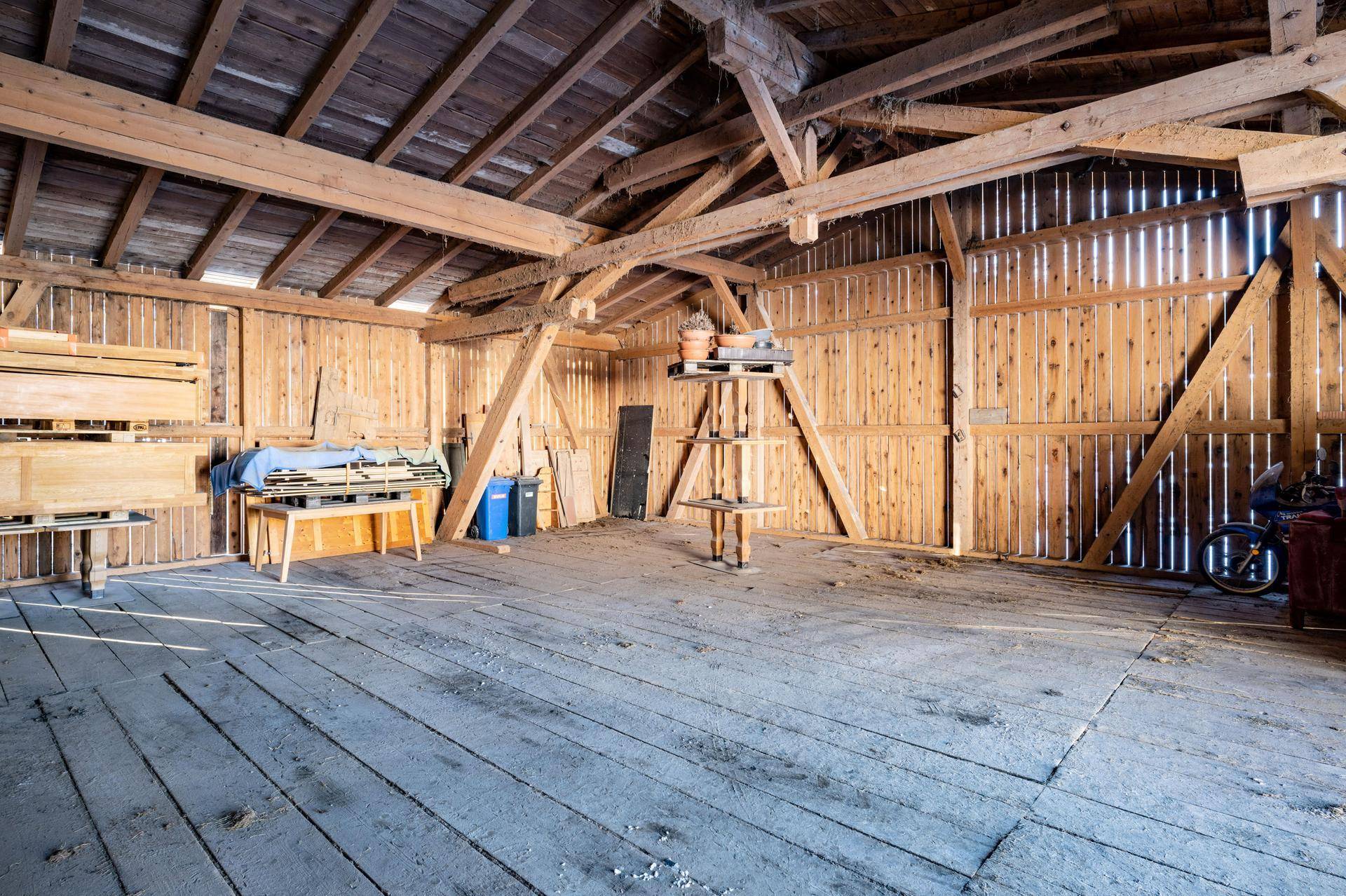 Großer Dachboden mit sichtbaren Holzbalken und Holzverkleidung, ideal als Lagerraum.