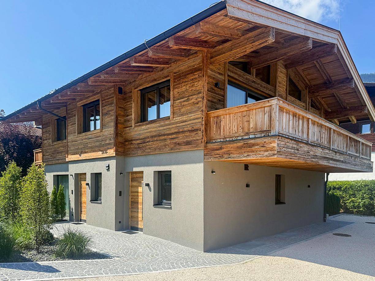 Attraktives Holzchalet mit moderner Architektur und Balkonen in alpiner Umgebung.