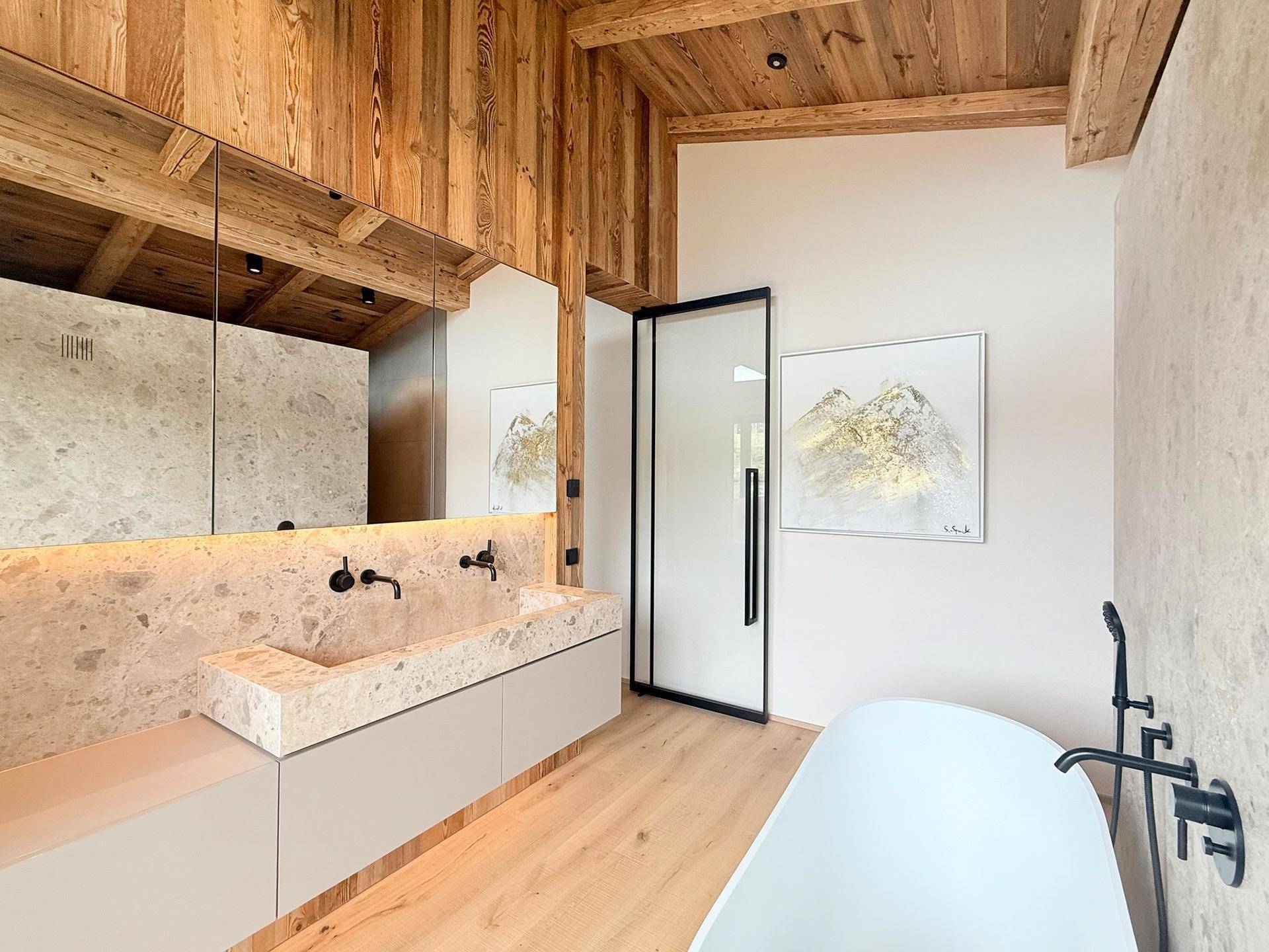 Modernes Badezimmer mit freistehender Badewanne, Doppelwaschbecken und Holzfußboden.