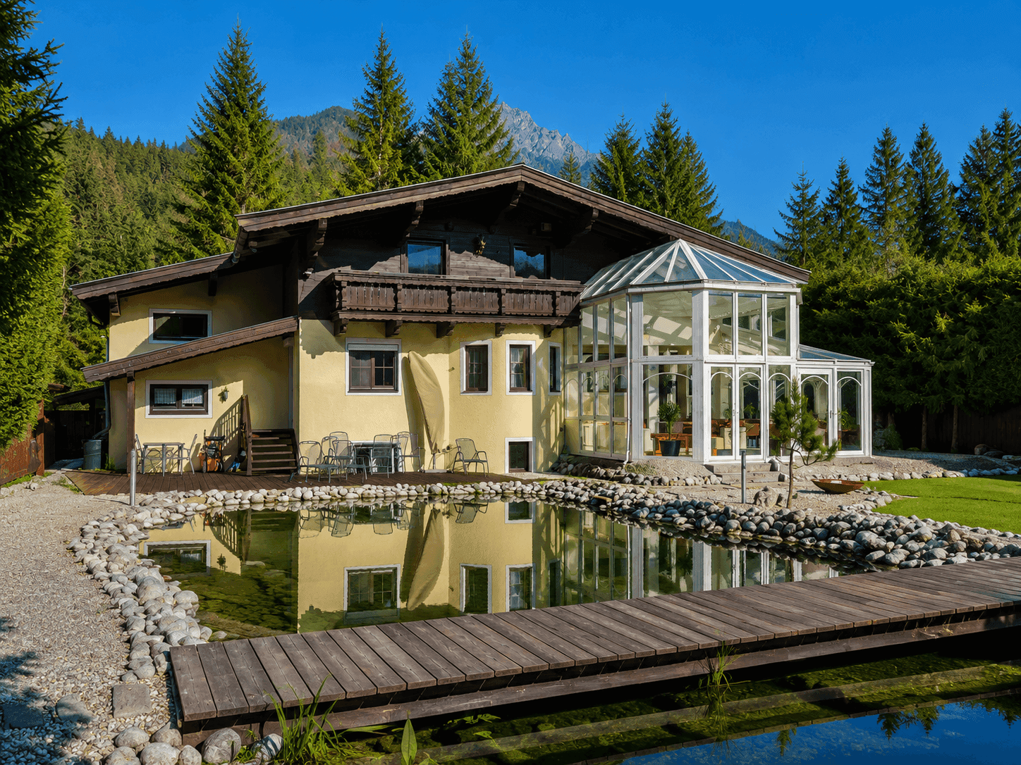 Idyllisches Anwesen mit großem Naturteich, der das Haus und den Wintergarten widerspiegelt.