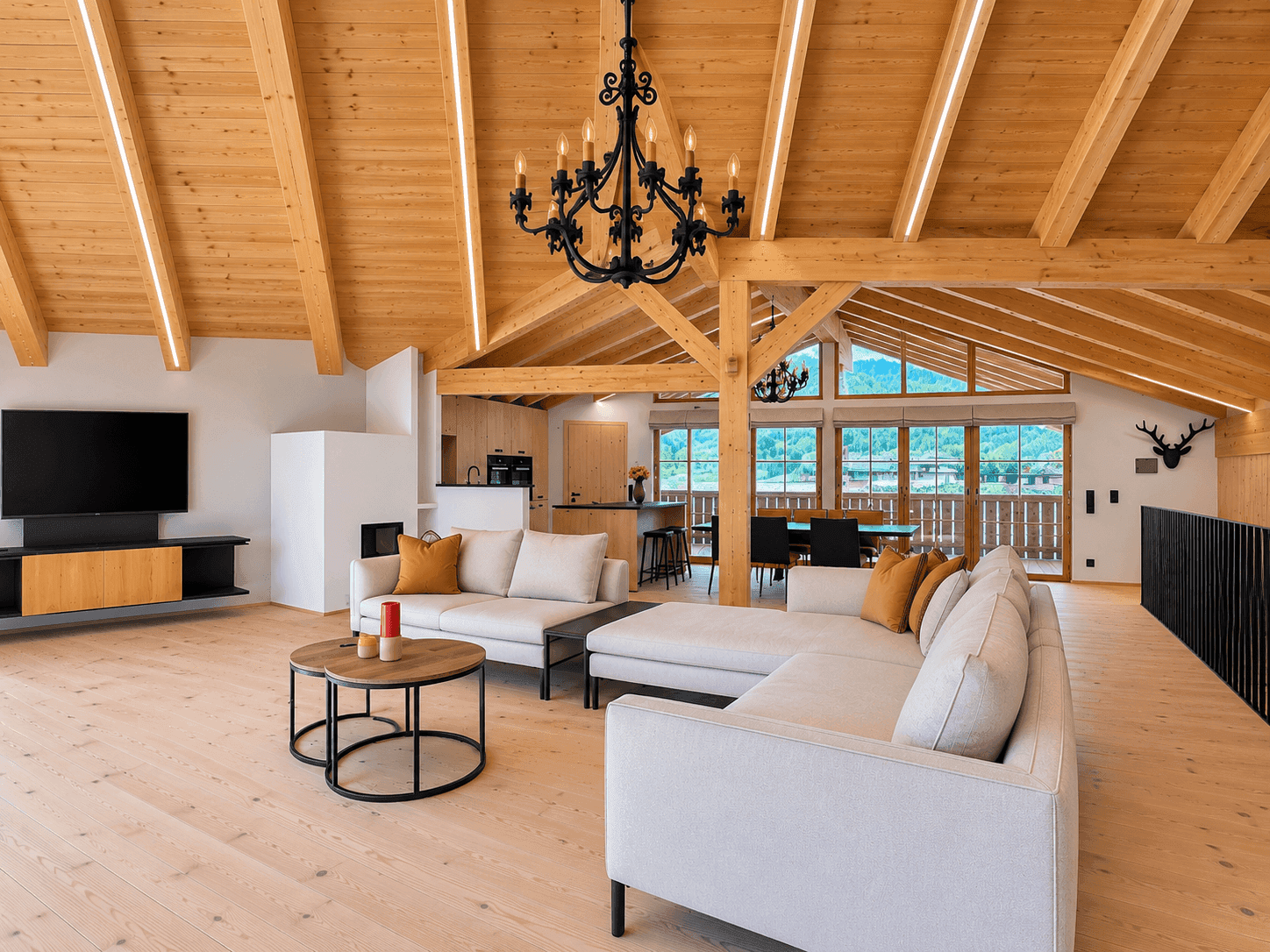 Gemütlicher Wohnbereich mit bequemer Couch, Holzbalken und Blick auf die umliegende Natur.