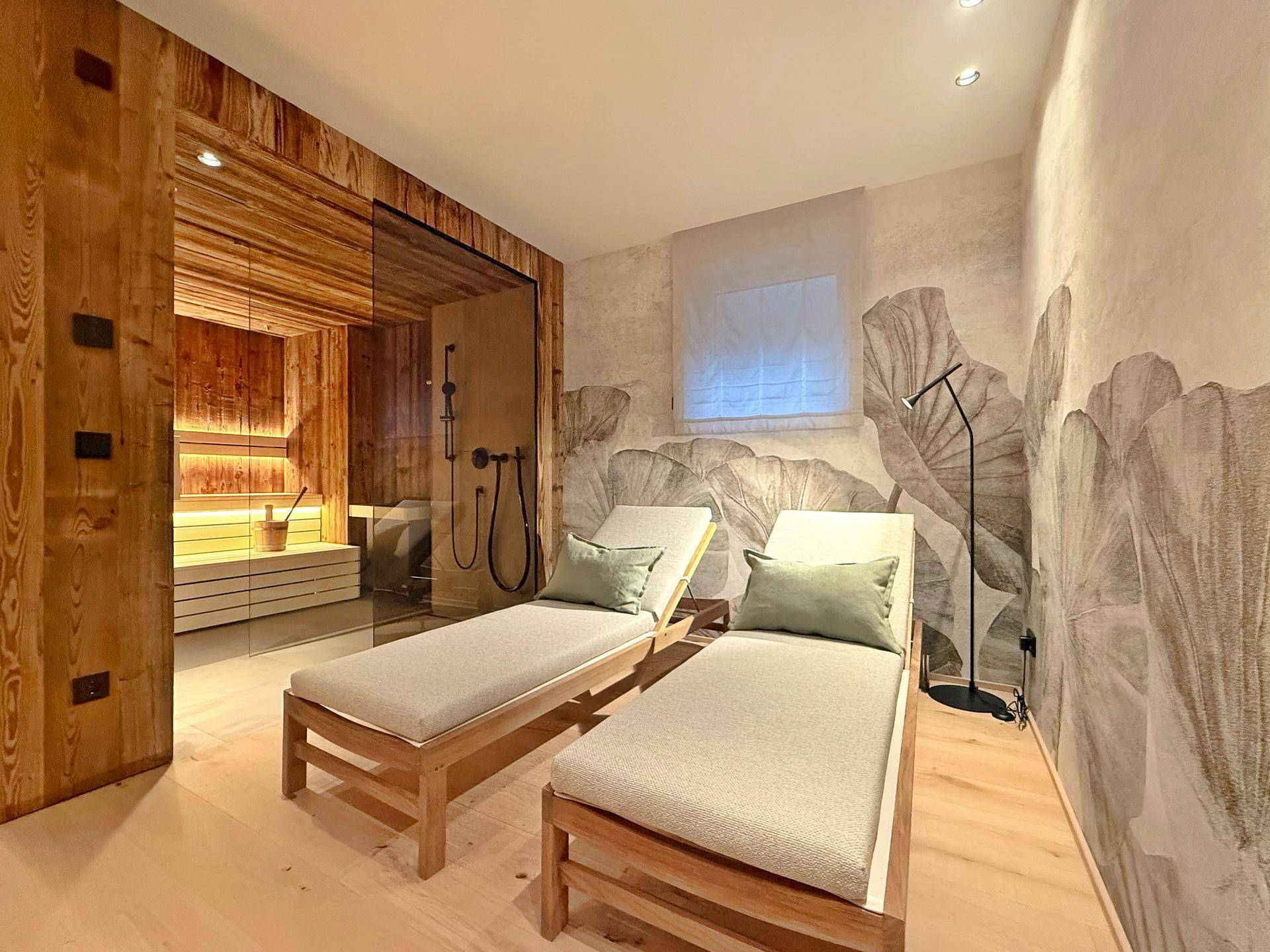 Entspannungsbereich mit Sauna, Liegen und dekorativer Wandgestaltung, ideal für Wellnessmomente.