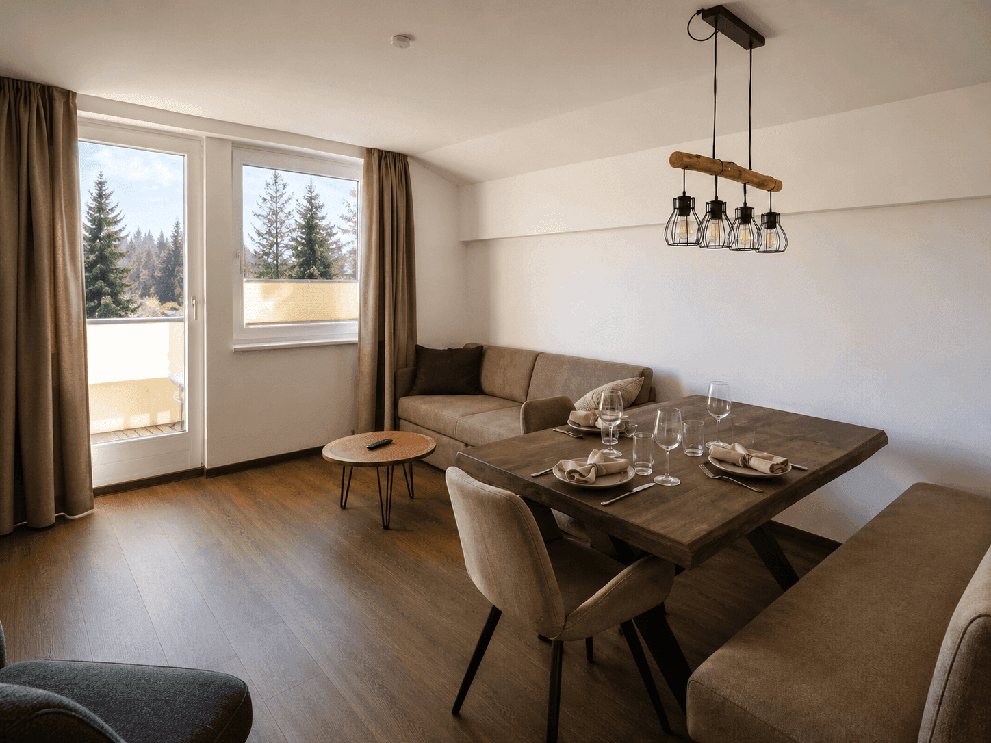 Heller Wohn- und Essbereich mit Holzboden, bequemer Couch und Zugang zum Balkon.