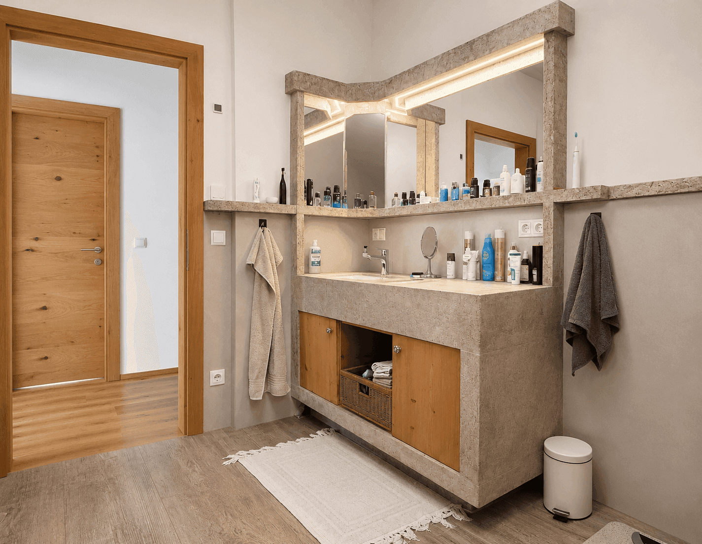 Modernes Badezimmer mit großem Waschtisch, integriertem Spiegel und Holzelementen.