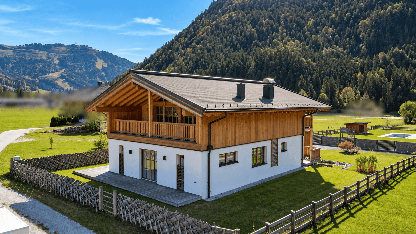 Traditionelles Holzhaus im alpinen Stil mit Satteldach und weitläufigem Gartenbereich.