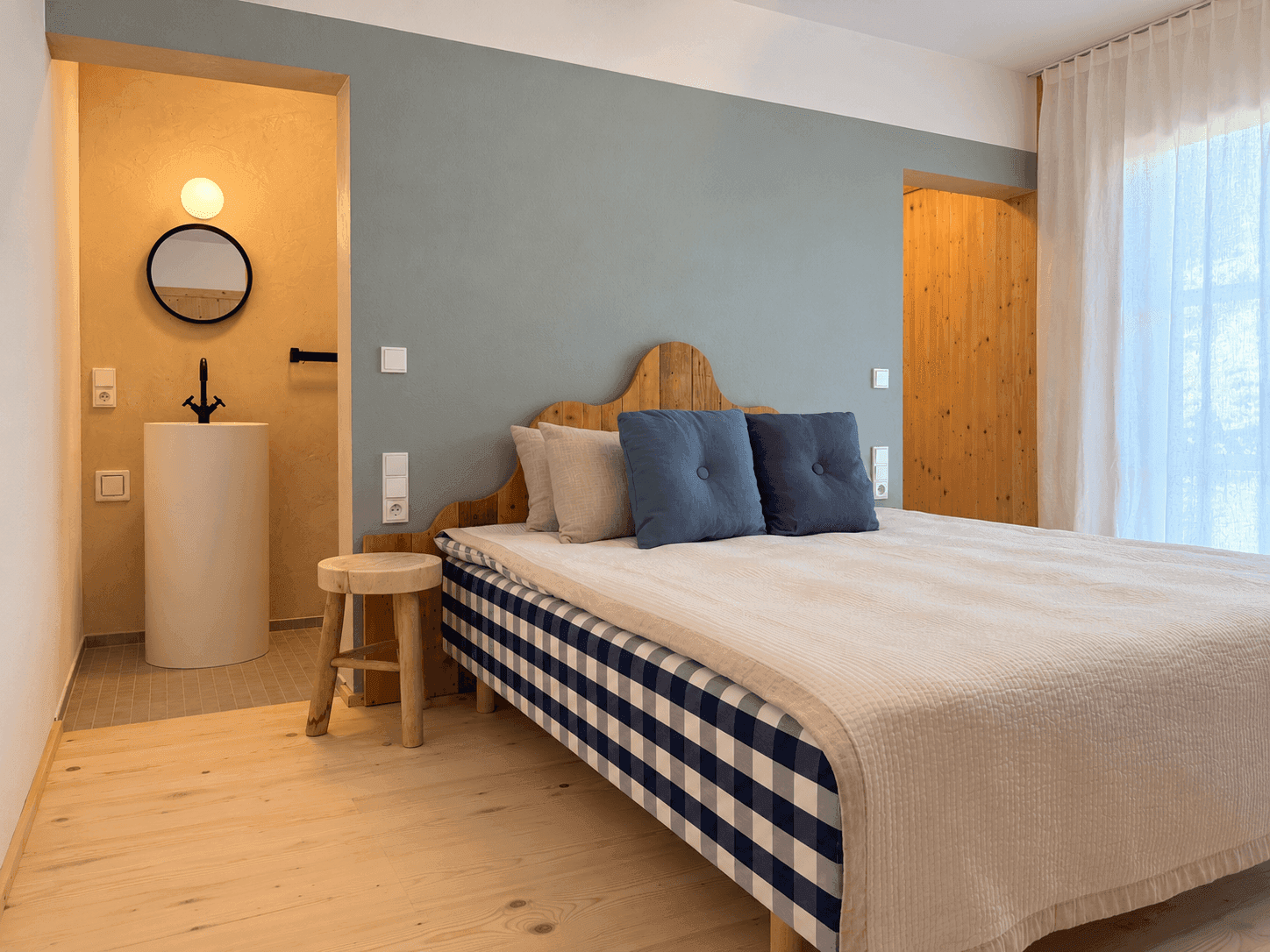 Stilvolles Schlafzimmer mit Holzboden, integriertem Waschbecken und Zugang zum Balkon.