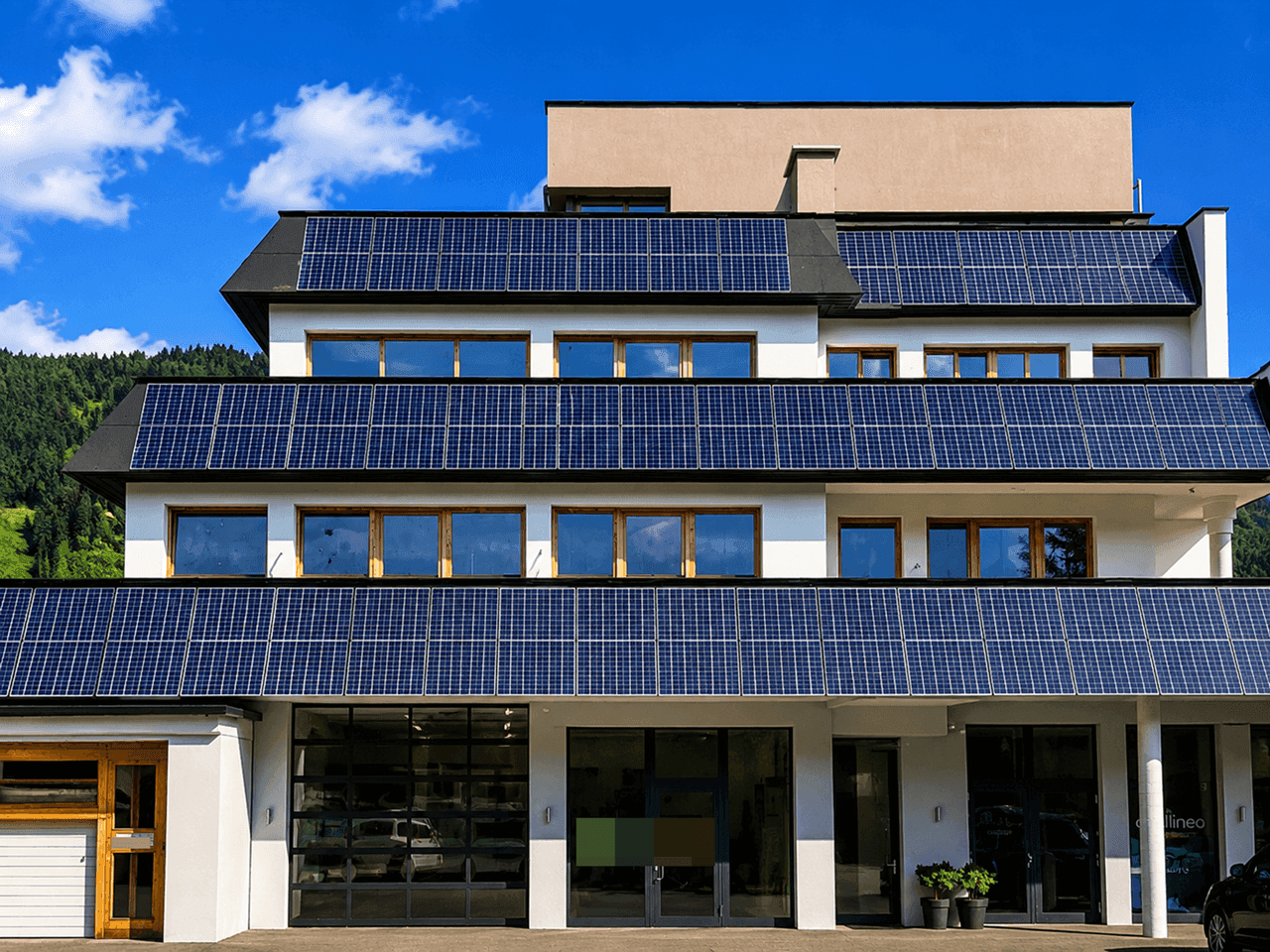 Frontansicht eines modernen Gebäudes mit zahlreichen Solarpaneelen auf den gestuften Ebenen und großen Glasfronten im Erdgeschoss.