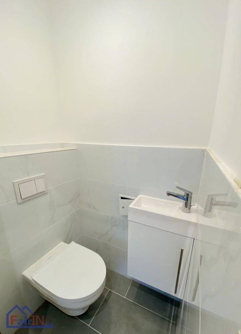 Modernes Gäste-WC mit wandhängender Toilette und kleinem Waschbeckenunterschrank.