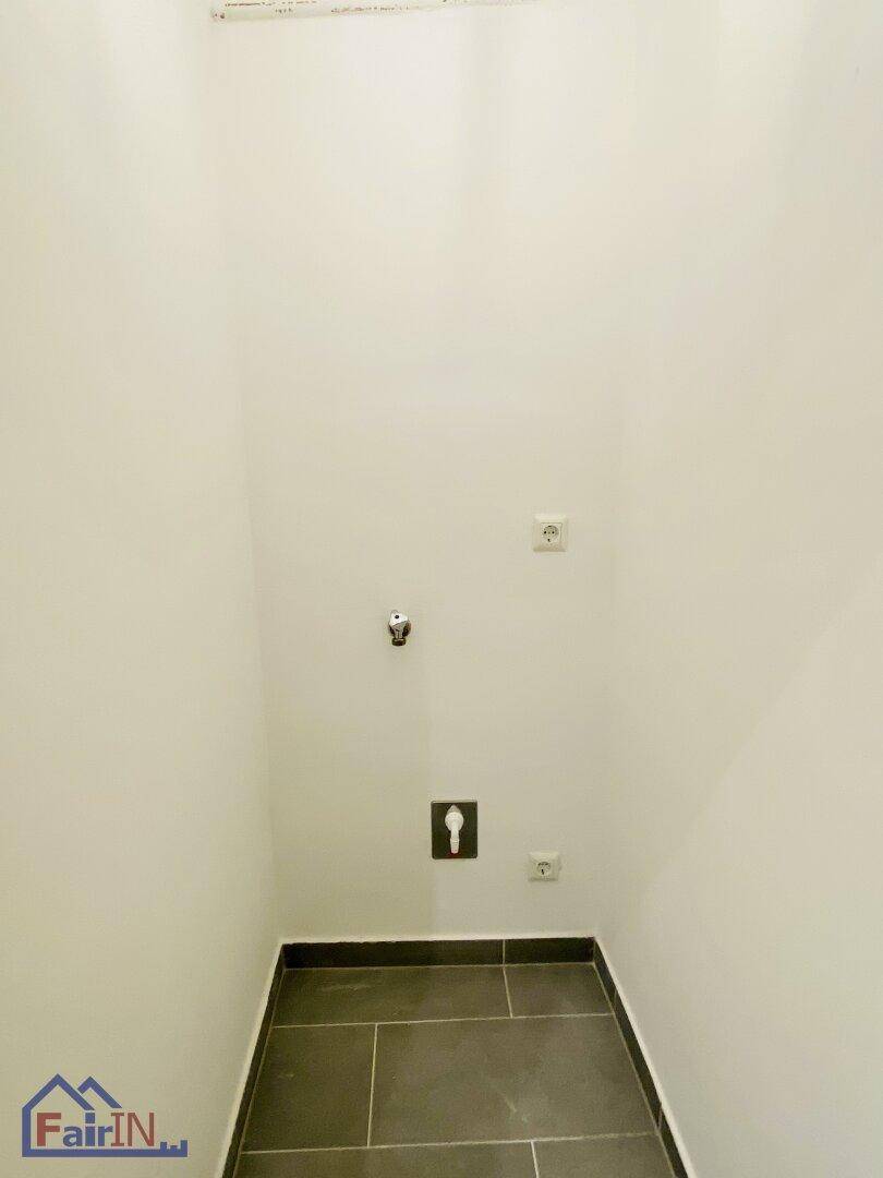 Kleiner Hauswirtschaftsraum mit Fliesenboden und Anschlüssen für Waschmaschine oder Trockner.