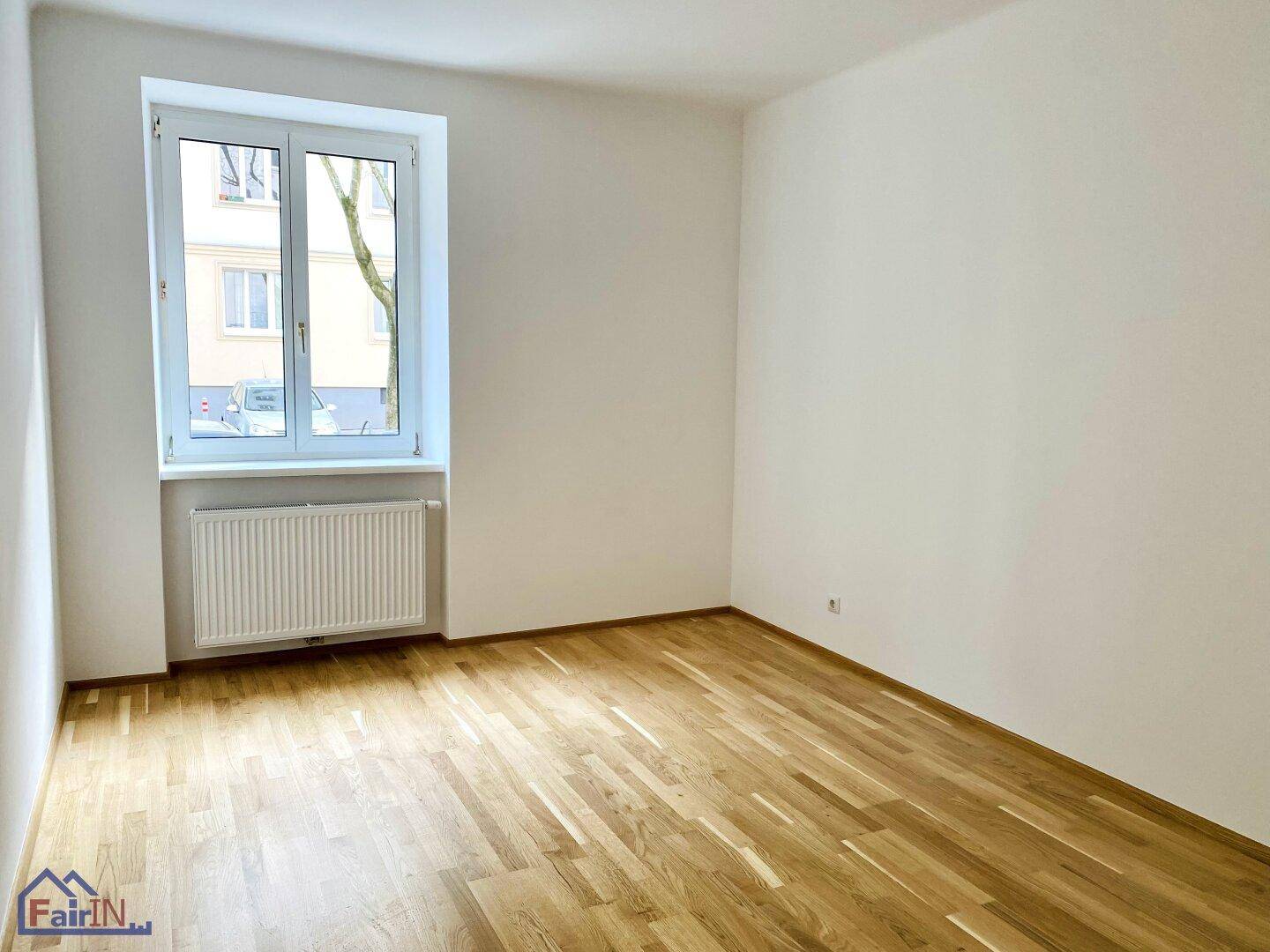 Helles Zimmer mit Parkettboden und einem Fenster, das den Raum gut mit Tageslicht versorgt.