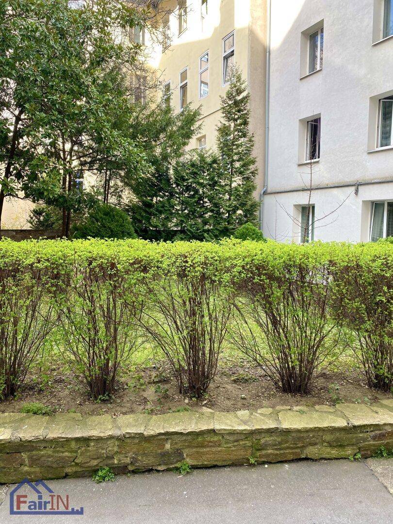 Gepflegte Hecke und Grünflächen vor der Fassade eines Wohngebäudes.