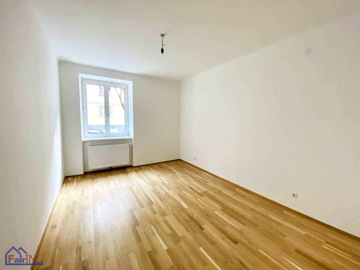 Geräumiges, helles Zimmer mit Holzparkett und einem Fenster, das den Raum gut belichtet.