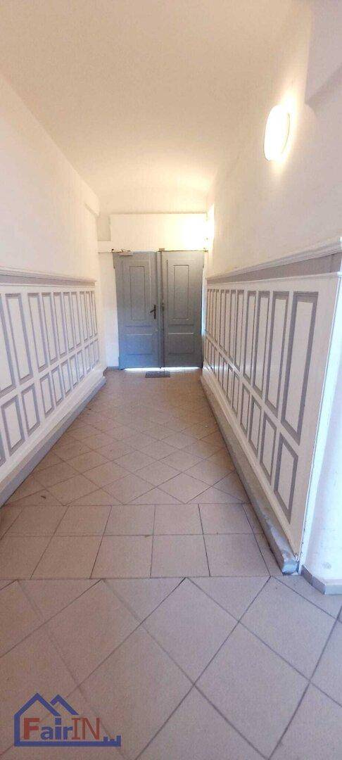 Langer Flur mit gemusterten Wandpaneelen und Fliesenboden, führt zu Doppeltüren.