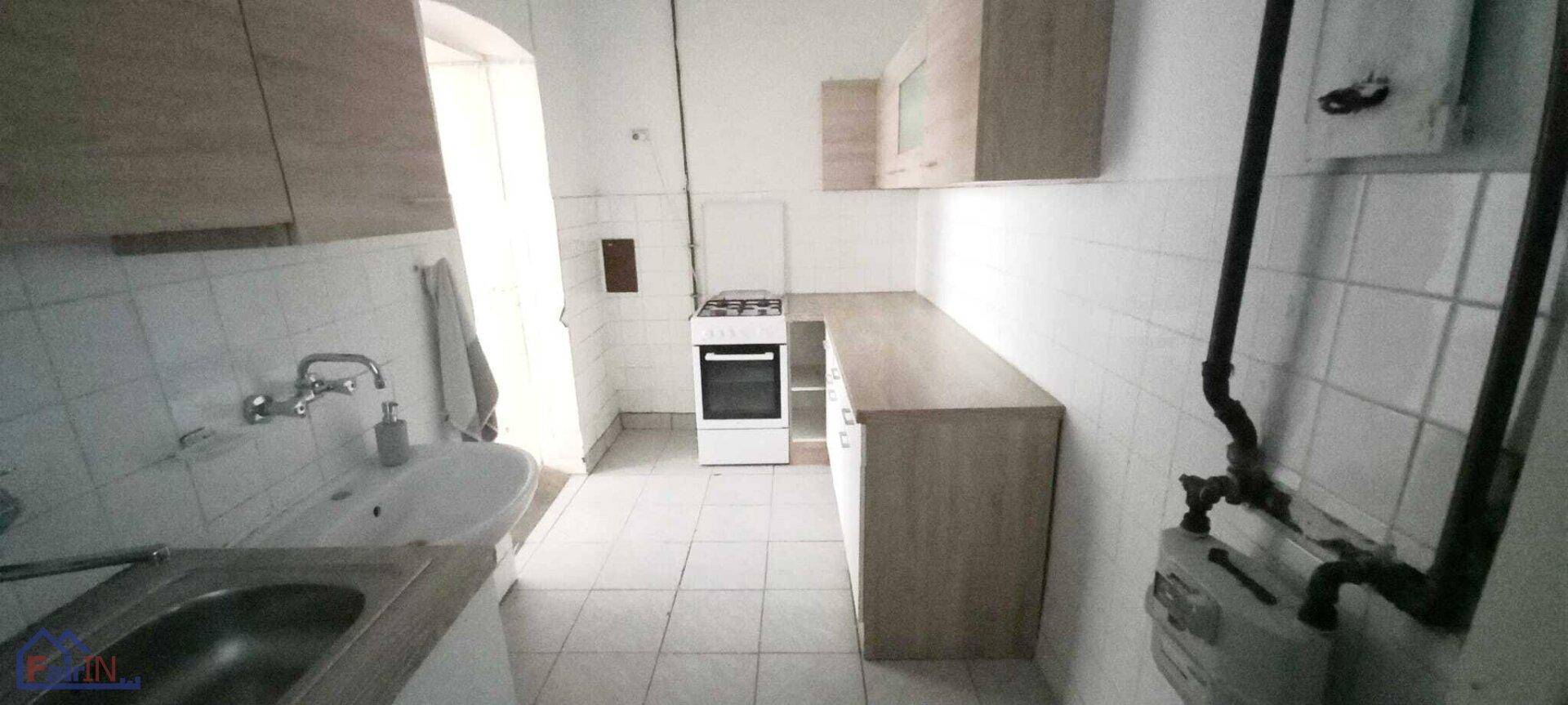 Einfache Küche mit Fliesenboden, Spüle und Gasherd, bereit zur Modernisierung.
