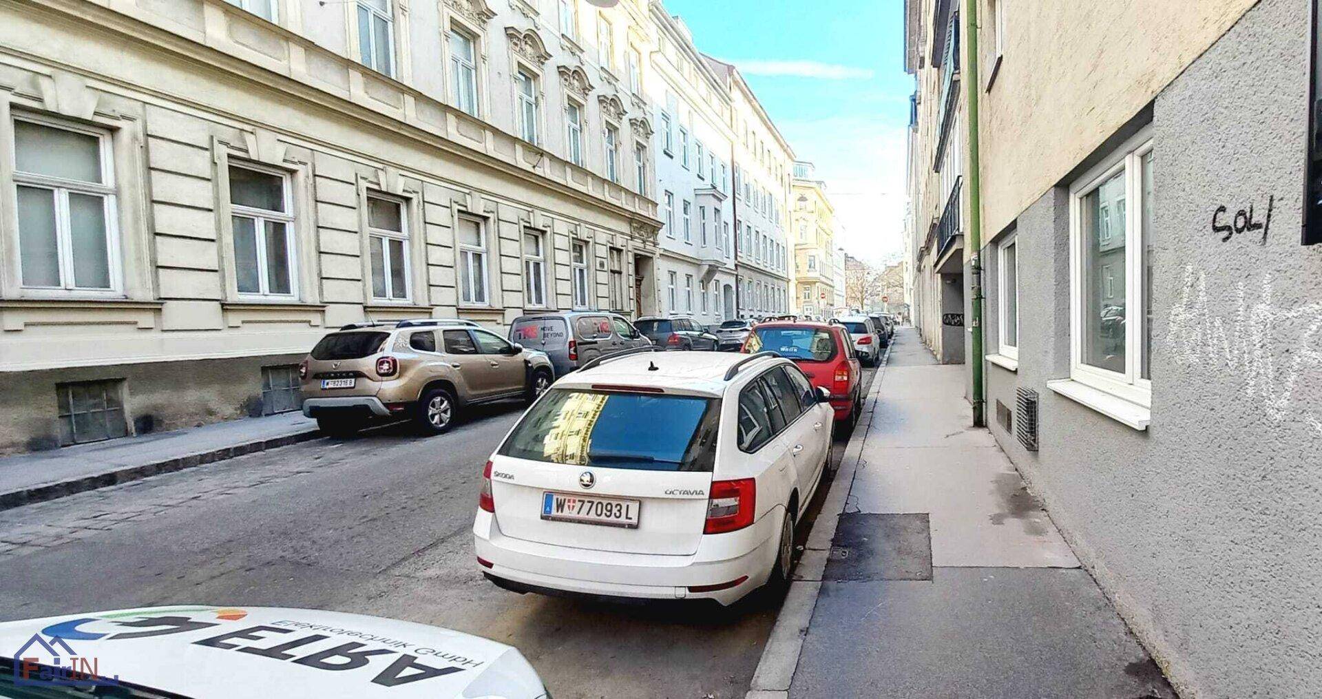 Belebte Straße mit parkenden Autos und historischen Fassaden in der Stadt.