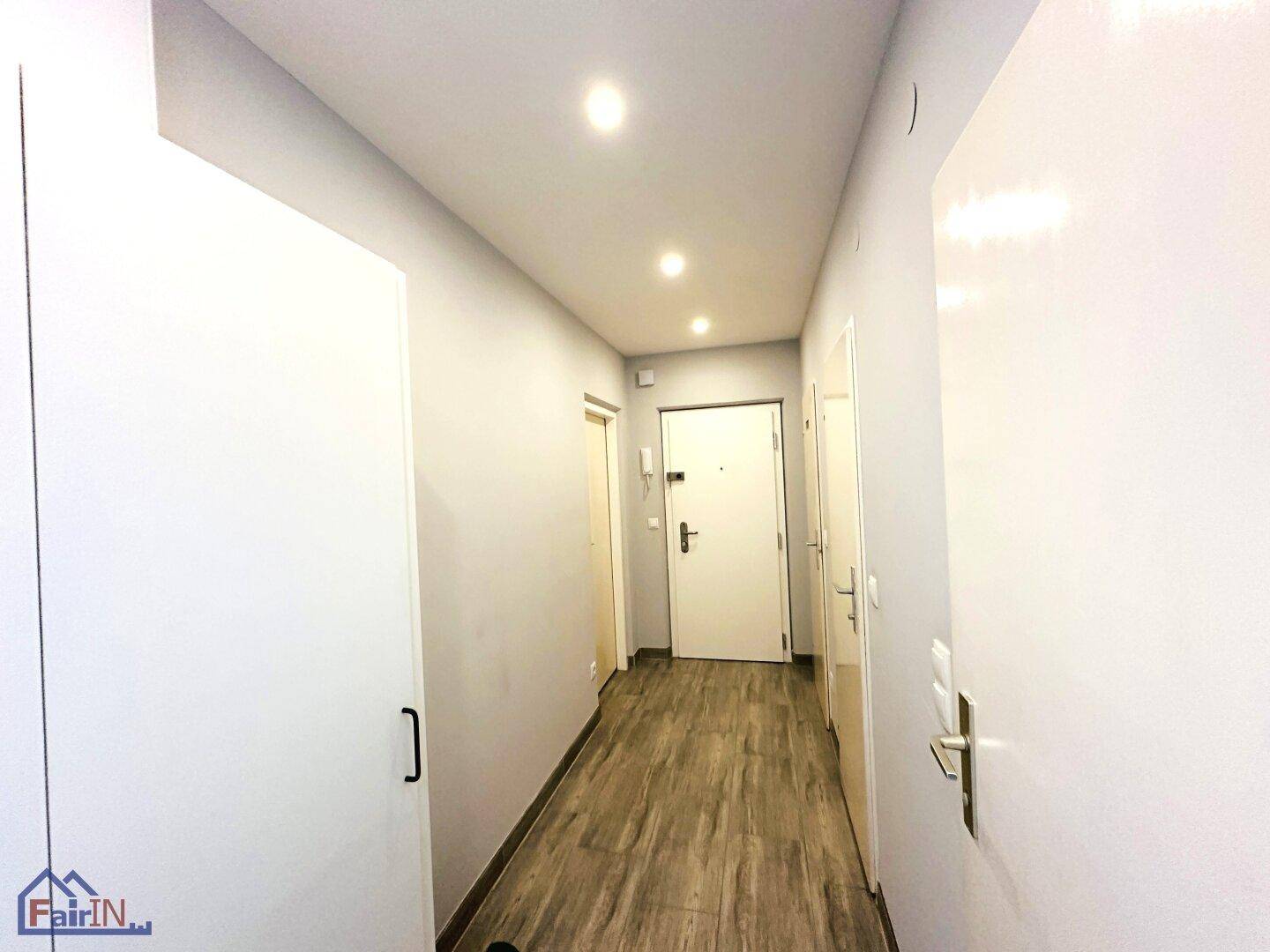 Heller Flur mit Einbauschränken, Holzoptikboden und integrierten Deckenspots.