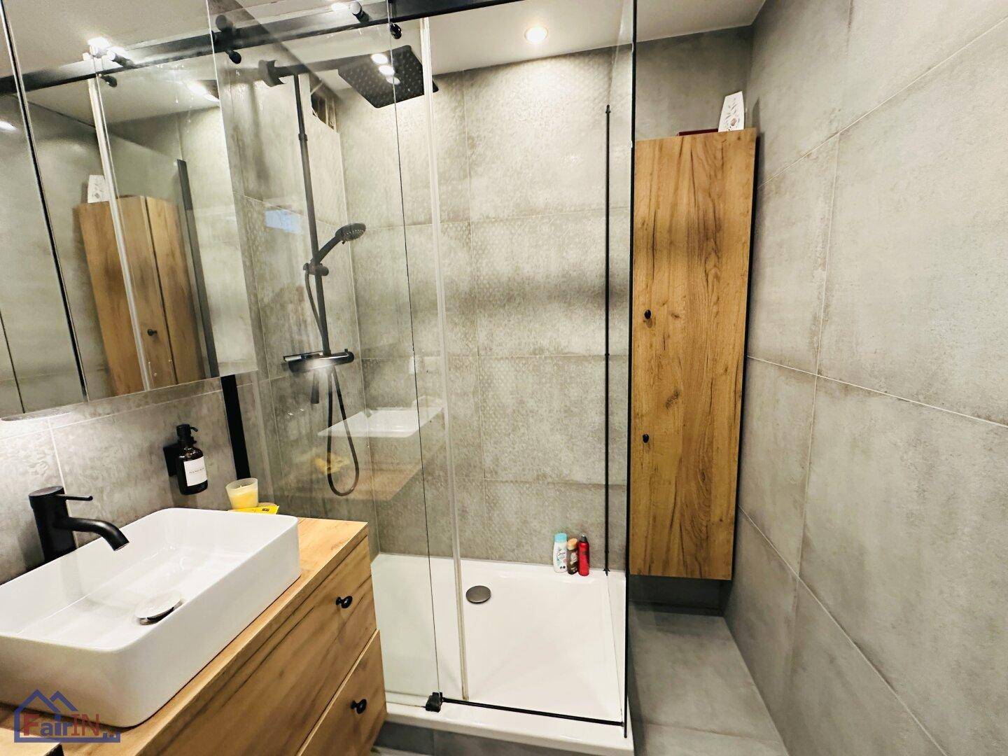 Modernes Badezimmer mit begehbarer Dusche, Holzwaschtisch und großformatigen grauen Fliesen.