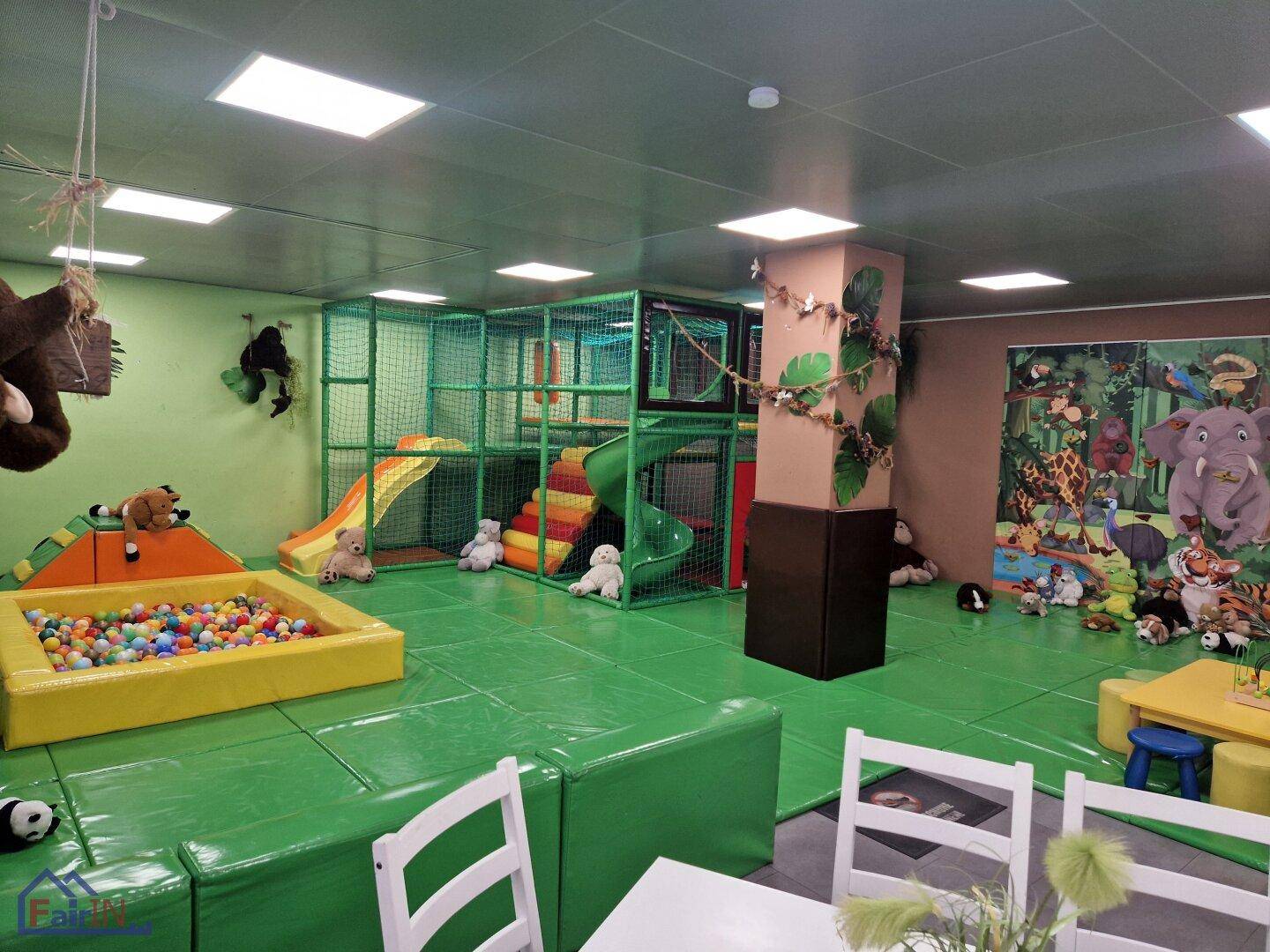 Detailansicht des Indoor-Spielplatzes mit Rutschen, Klettergerüst und Bällebad, dekoriert mit Dschungelmotiven.