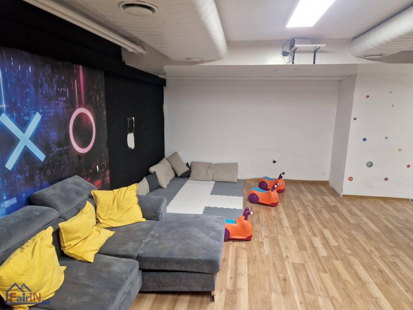 Entspannter Loungebereich mit bequemen Sofas und Spielmatten, ideal für Kinder und Jugendliche.