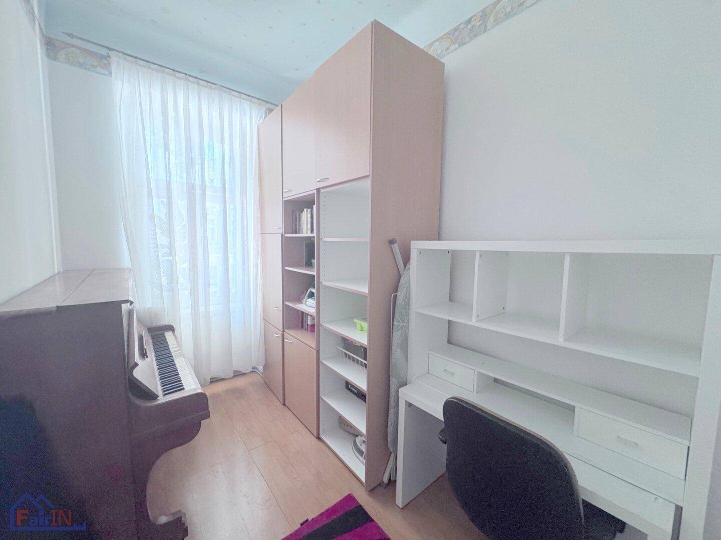 Arbeitszimmer mit Klavier, Schreibtisch und Bücherregalen, hell und funktional gestaltet.
