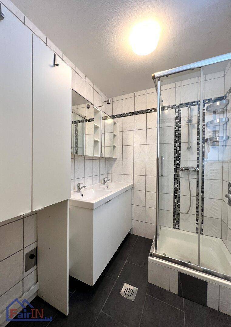 Modernes Badezimmer mit Doppelwaschbecken, Duschkabine und Fliesen in Schwarz-Weiß.