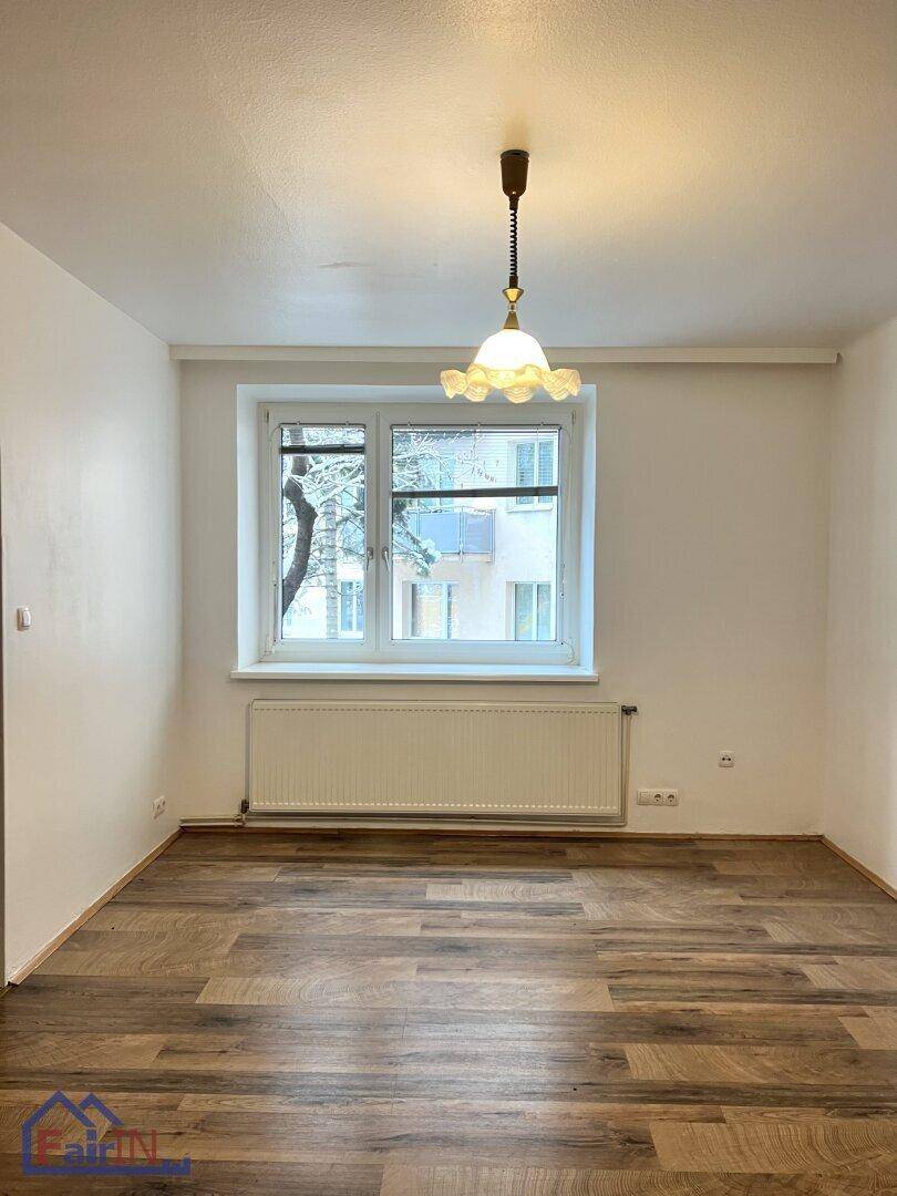 Geräumiger Wohnbereich mit Holzfußboden und Fenster mit Blick auf die Umgebung.