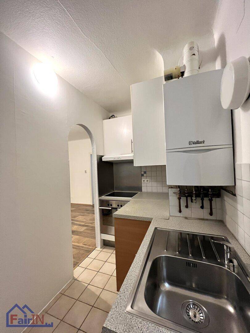 Küchenzeile mit Spülbecken, Arbeitsplatte und Gastherme an der Wand.