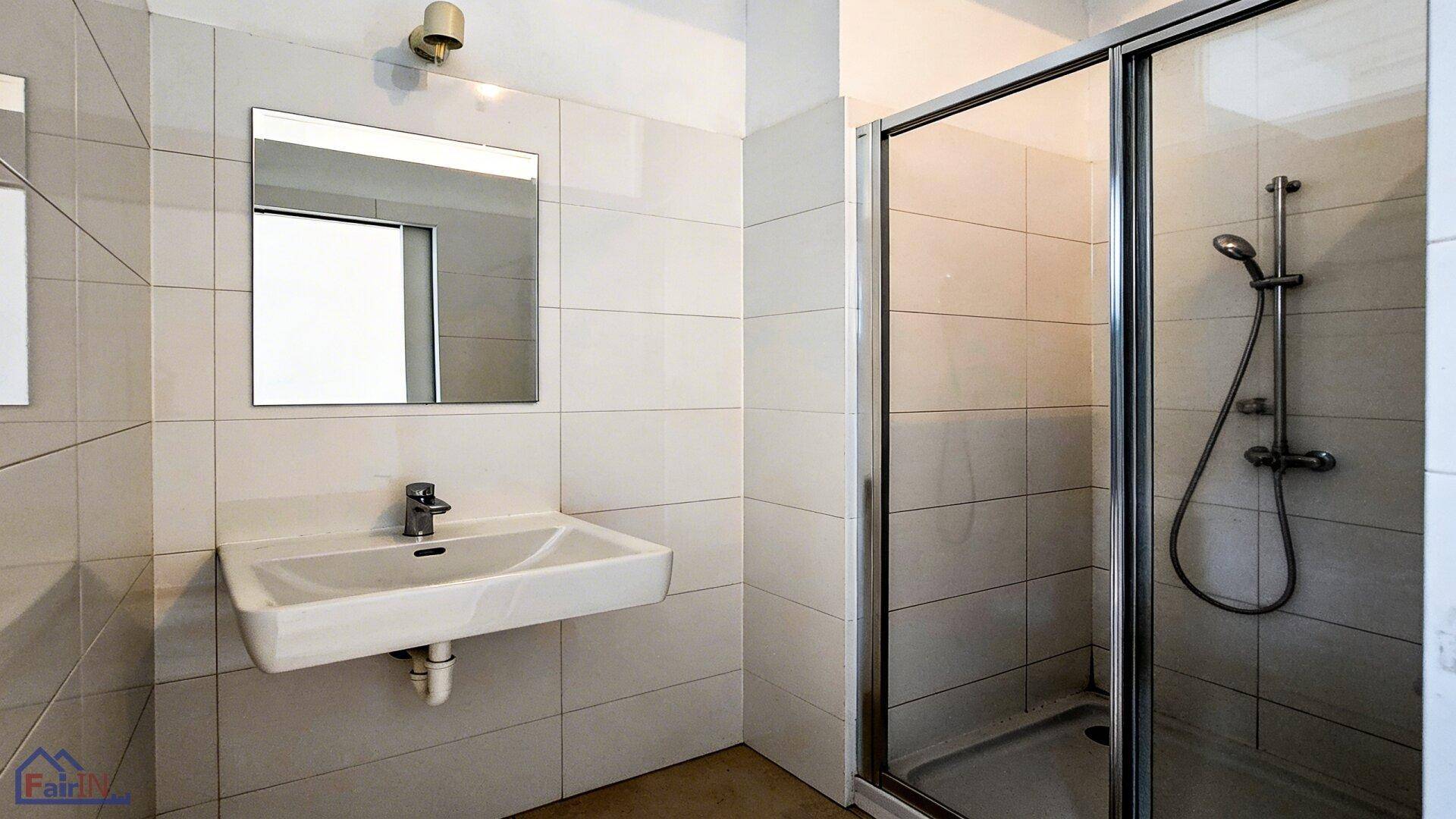 Modernes Badezimmer mit weißen Fliesen, Einzelwaschbecken und einer Duschkabine.