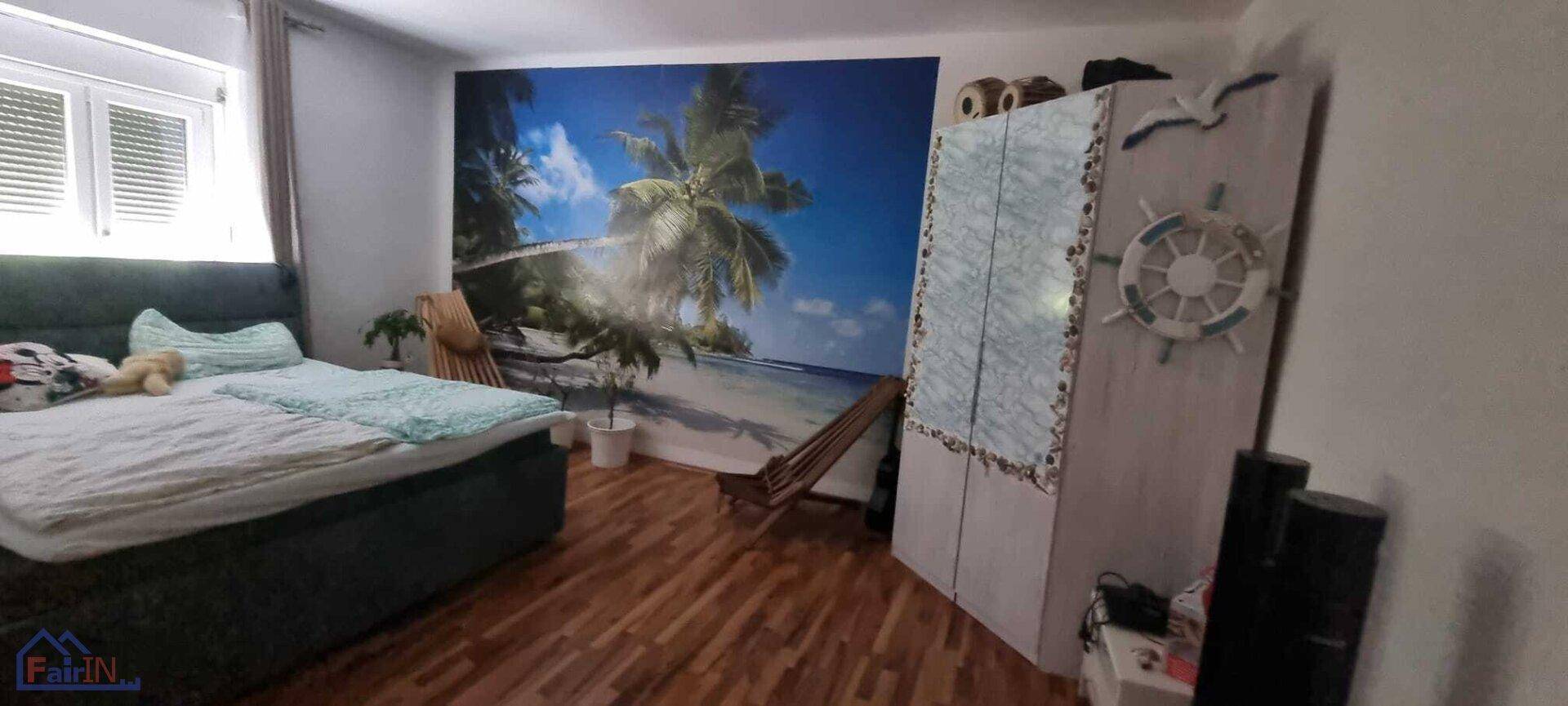 Gemütliches Schlafzimmer mit Doppelbett, Kleiderschrank und einer dekorativen Strandtapete an der Wand.