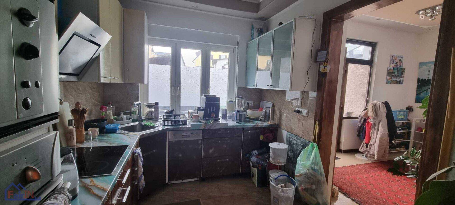 Funktionale Küche mit Spüle, Geräten und einem Fenster, das den Raum mit Tageslicht versorgt.