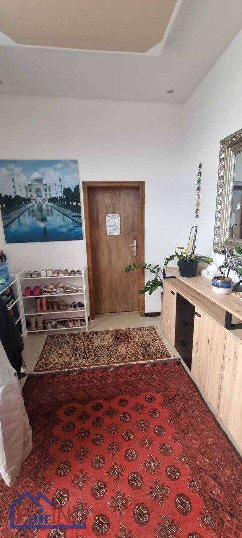 Geräumiger Flur mit Schuhregal, Teppich und einem Wandbild, das eine angenehme Atmosphäre schafft.