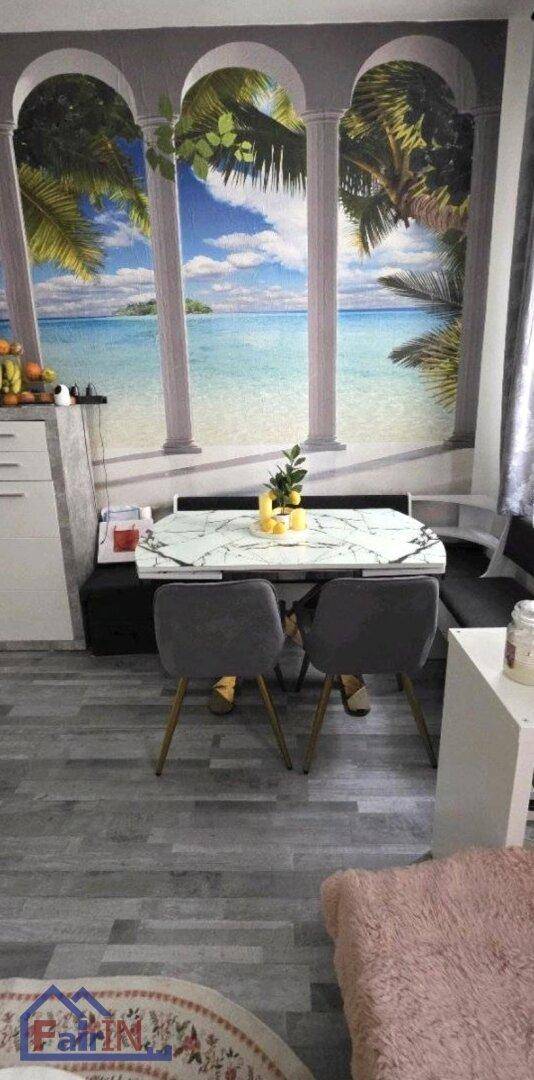Gemütlicher Essbereich mit modernem Tisch, Stühlen und einer Wandtapete mit tropischem Strandmotiv.