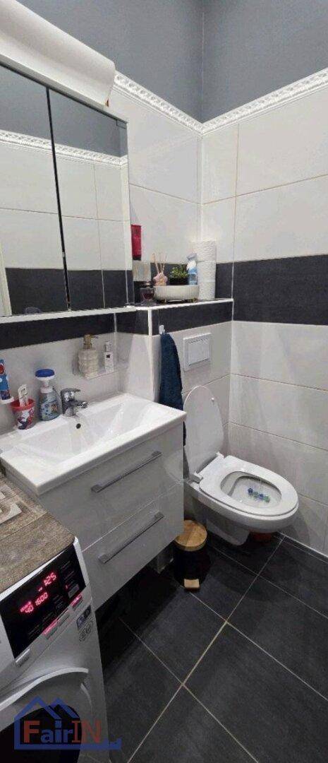 Badezimmer mit Toilette, Waschbecken, Spiegelschrank und einer Waschmaschine.