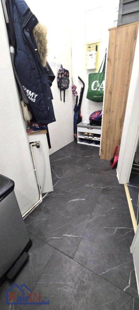 Flur oder Eingangsbereich mit dunklem Fliesenboden, Garderobe und Schuhregal.