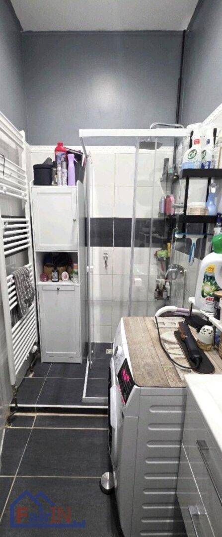 Badezimmer mit Duschkabine, beheiztem Handtuchhalter und Waschmaschine.