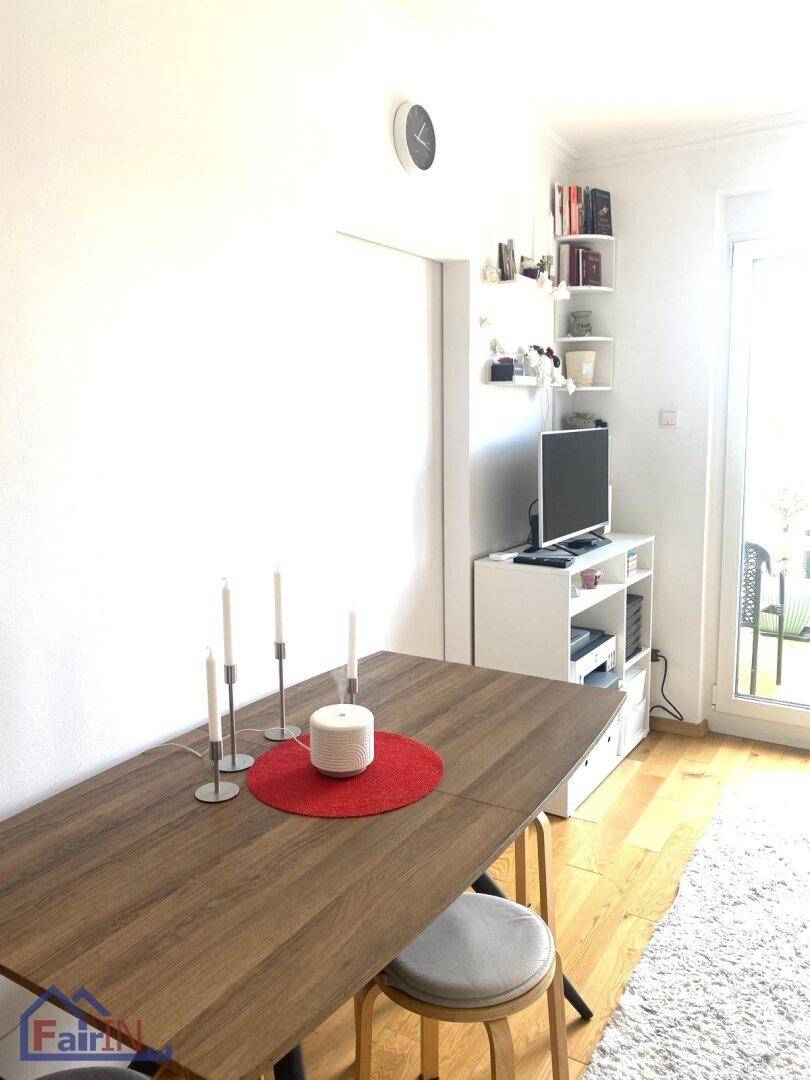 Heller Wohn- und Essbereich mit Holzboden, Zugang zum Balkon und moderner Einrichtung.