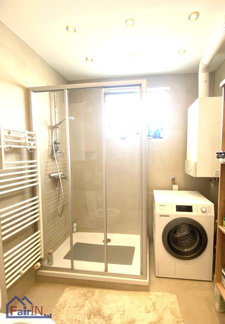 Modernes Badezimmer mit Duschkabine, Waschmaschine und Handtuchheizkörper.