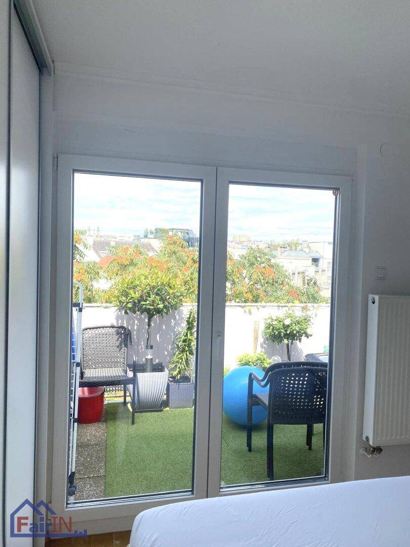 Blick vom Schlafzimmer auf die begrünte Terrasse mit Sitzgelegenheiten und viel Tageslicht.
