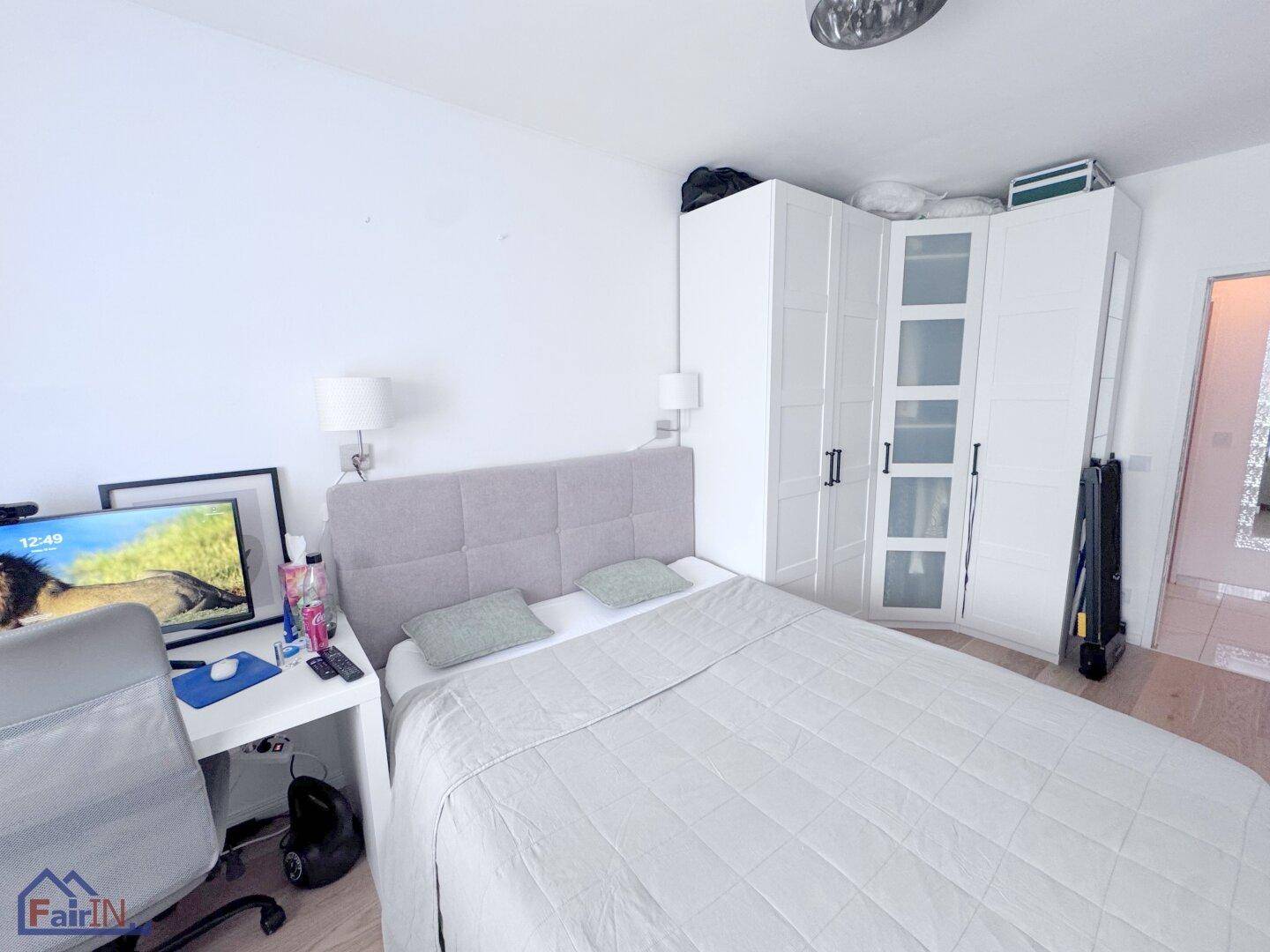 Helles Schlafzimmer mit Doppelbett, Schreibtisch und geräumigen weißen Kleiderschränken.
