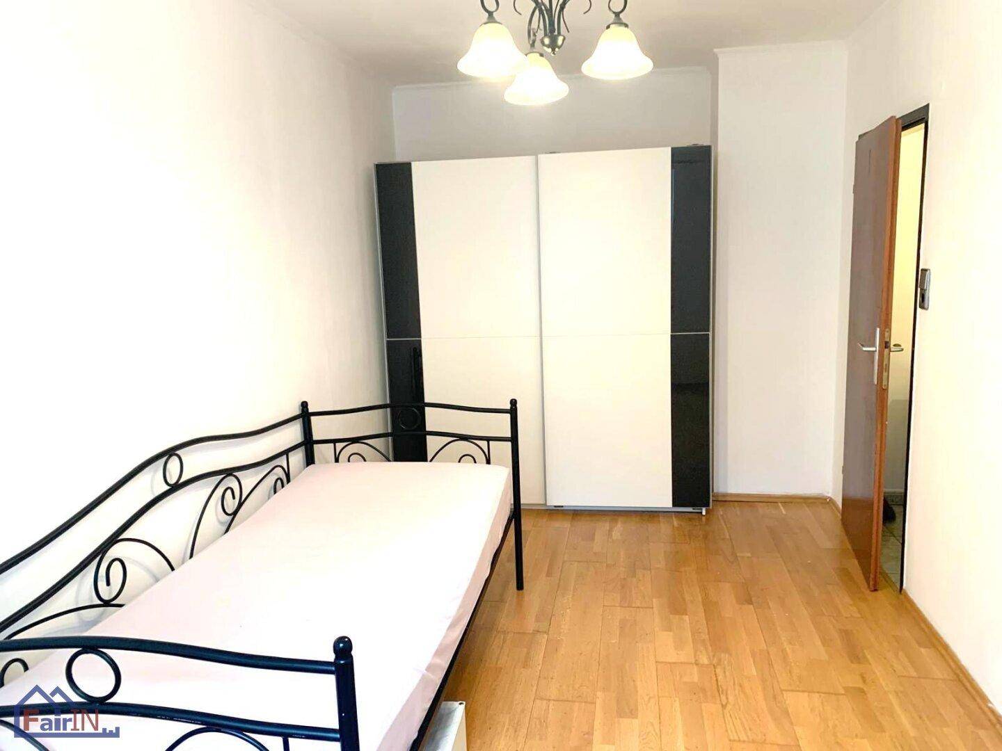 Schlafzimmer mit Einzelbett, modernem Kleiderschrank und Parkettboden.