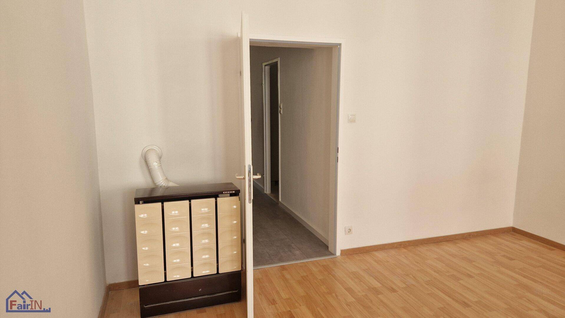 Leerer Raum mit Holzparkettboden und einem Schrank mit Anschluss für ein Gerät.