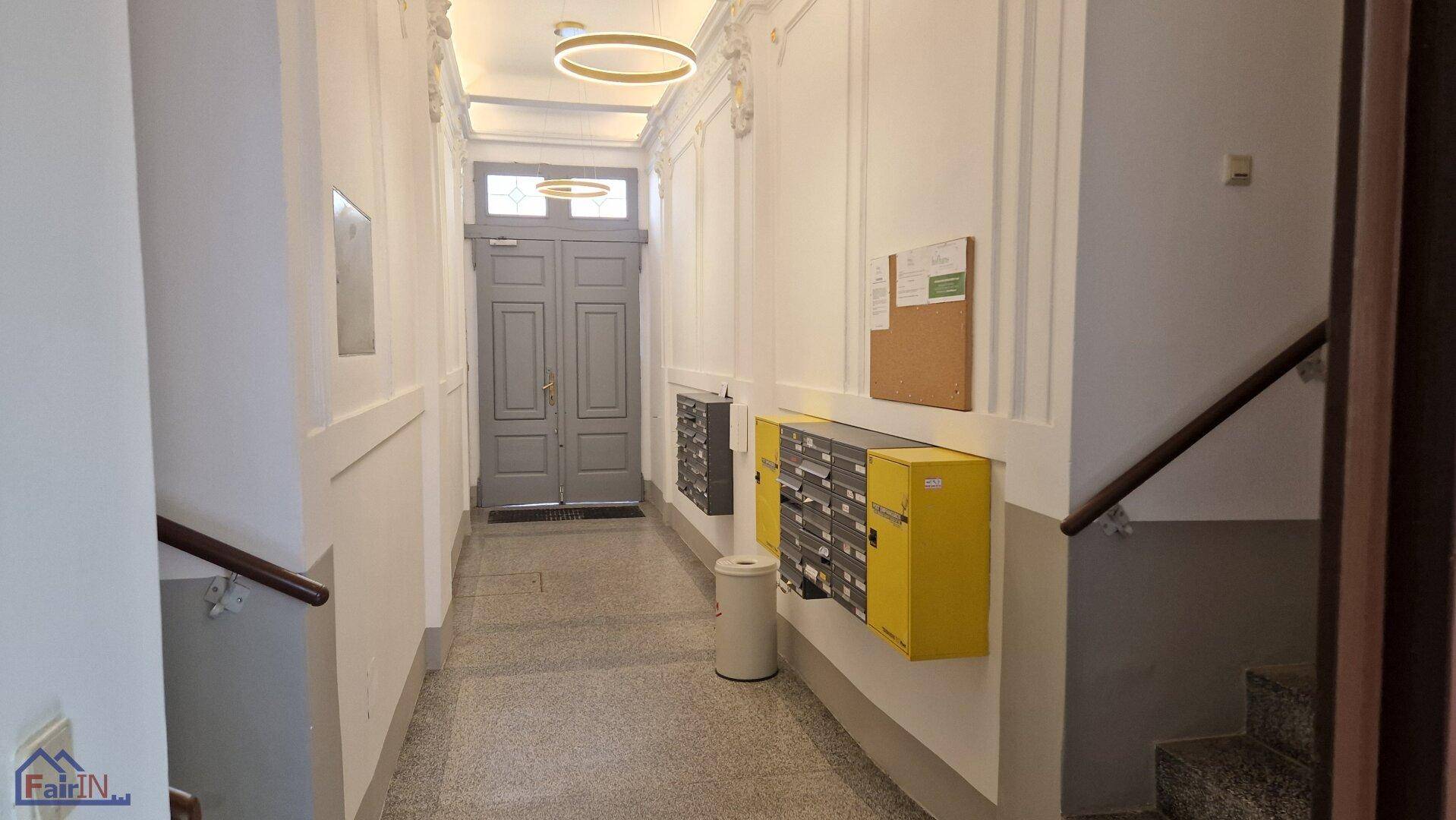 Eingangsbereich mit Briefkästen, Treppenhaus und Terrazzoboden im Altbau.