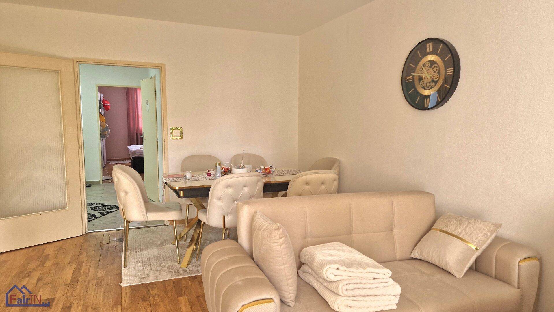 Heller Wohn- und Essbereich mit modernem Esstisch, beigem Sofa und Holzboden.