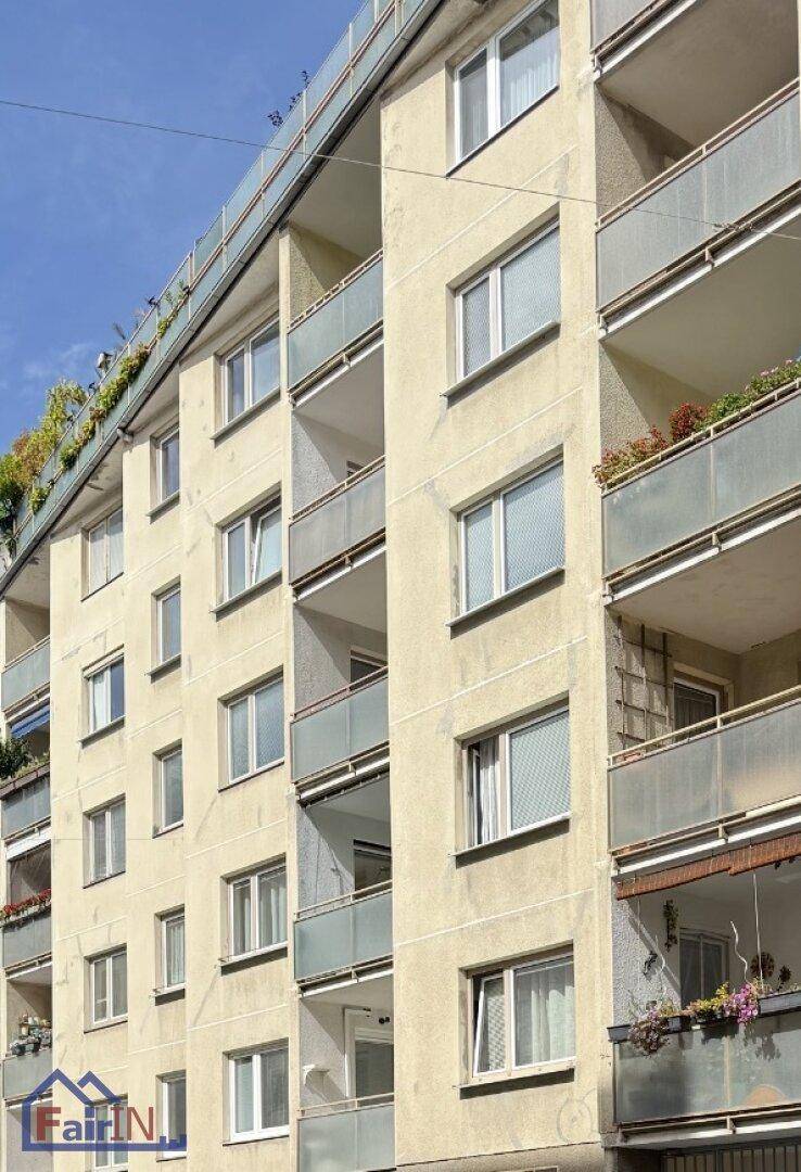 Fassade eines Mehrfamilienhauses mit mehreren Balkonen unter blauem Himmel.