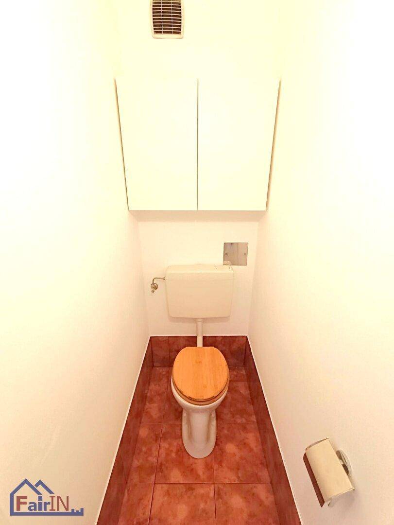 Kleine Gästetoilette mit Terrakotta-Fliesenboden, WC und praktischem Wandschrank.